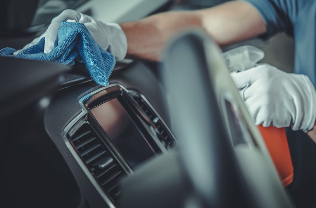 Car detailing professional cleaning the car dashboard and console.